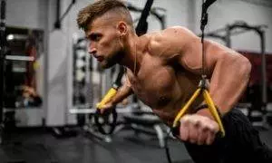 topless man in black pants holding black and yellow exercise equipment