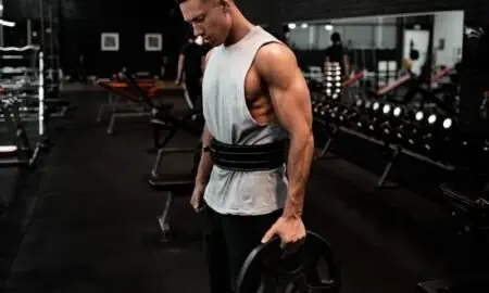 man in white tank top holding bumper plate