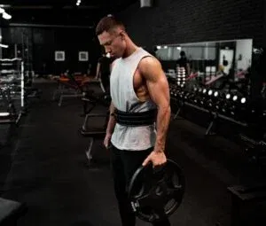 man in white tank top holding bumper plate